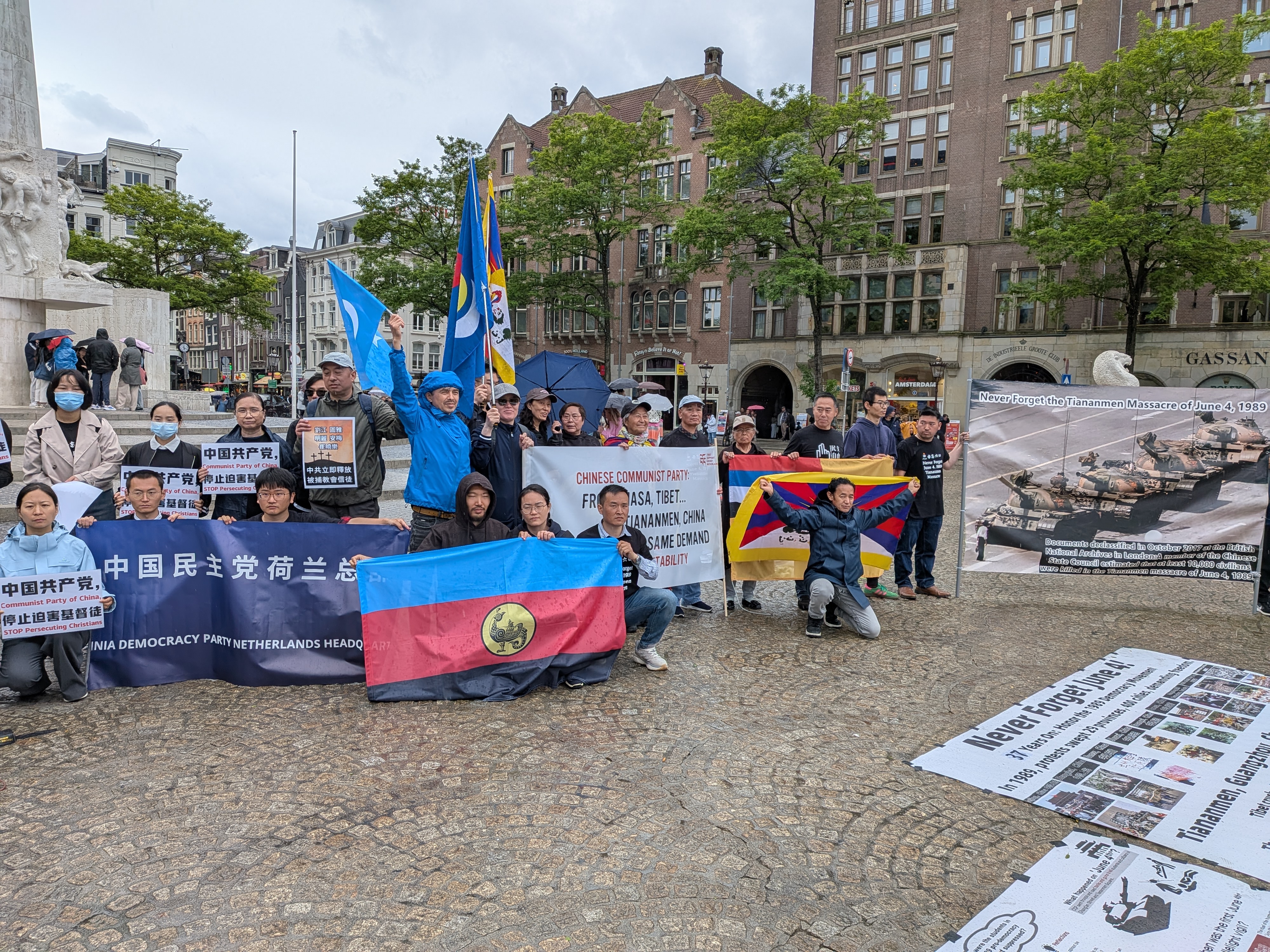 Deelnemers met de Tibetaanse vlag, de Zuid-Mongoolse vlag en een spandoek van de China Democracy Party op de Dam