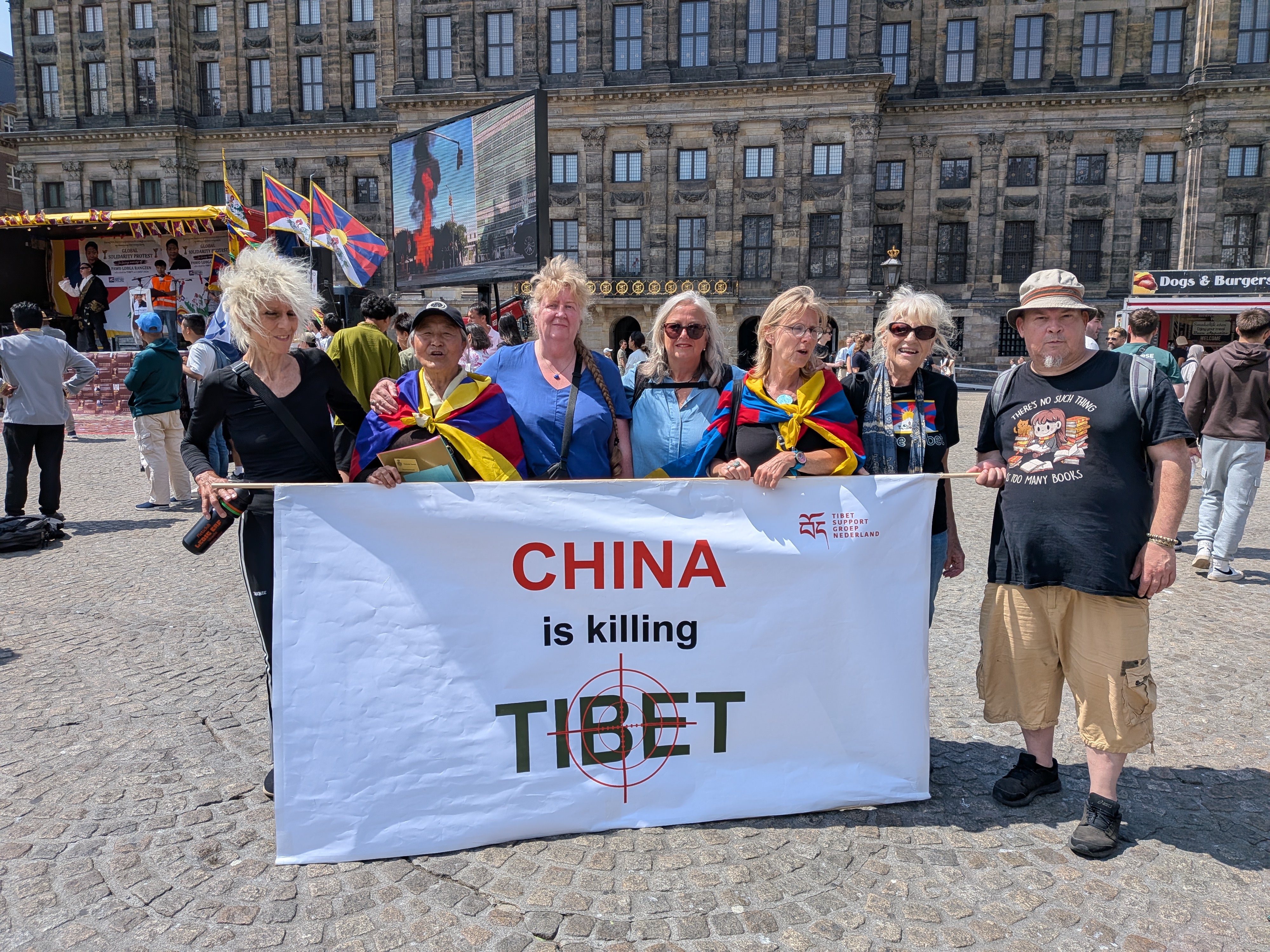 Deelnemers houden een spandoek vast met de tekst China is killing Tibet, met Tibetaanse vlaggen op de achtergrond