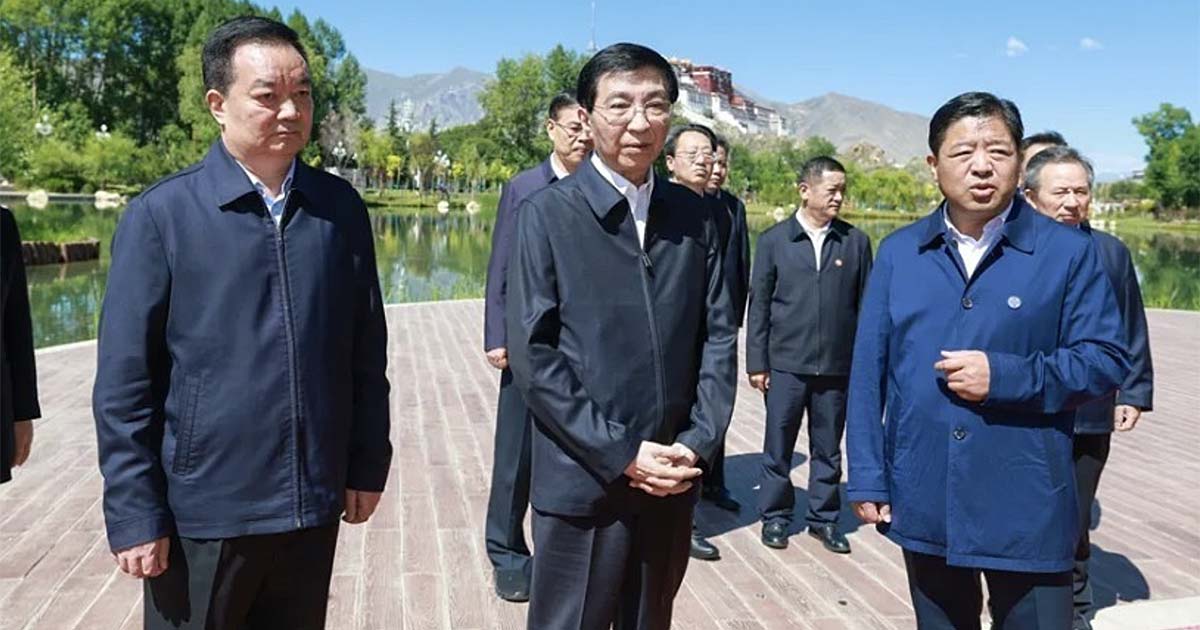 Wang Huning en partijfunctionarissen in donkere jasjes tijdens een inspectie in Lhasa, met het Potala-paleis op de achtergrond
